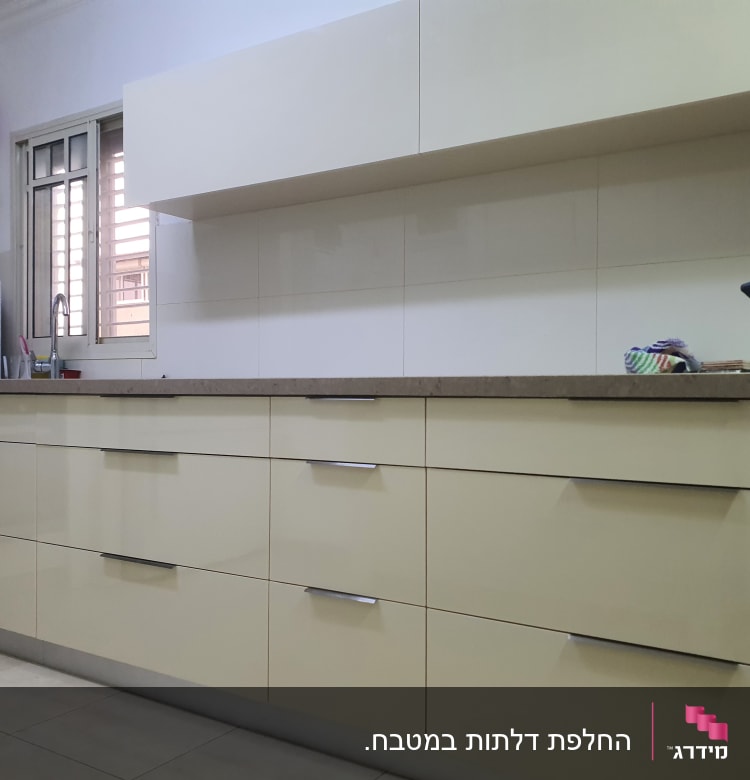 מטבח עם ארונות בהירים, כיור ומתקן מים